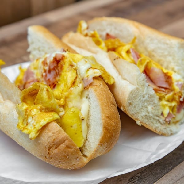 Two Mama Gina's breakfast sandwiches with scrambled eggs, cheese, and ham on a white plate.